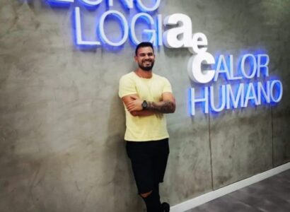 Colaborador Jamesson, da AeC, recostado na parede, com o letreiro Tecnologiaecalor humano na parede